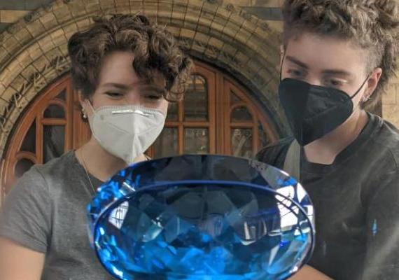 Two students observe a large blue gem